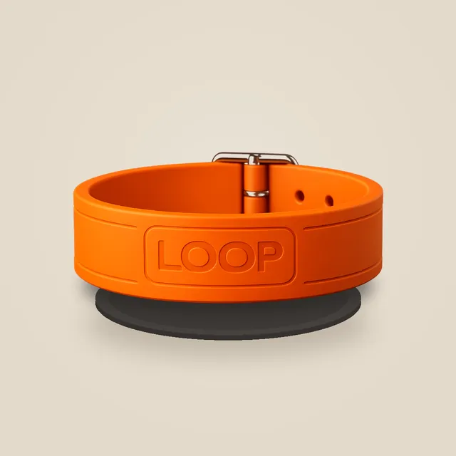 An orange LOOP collar resting on a round wireless charging pad
